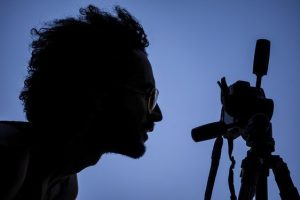 Mann der durch eine Kamera schaut und Bilder für sein Unternehmen aus der Baubranche macht